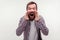 Attention! Portrait of enraged mad bearded man yelling loudly holding arms around mouth. white background