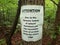 Attention warning about erosion sign on tree in woods