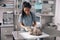 Attentive Asian lady veterinarian examines fluffy grey cat on table