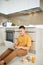 Attentive asian man using laptop while sitting on floor in kitchen