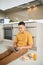 Attentive asian man using laptop while sitting on floor in kitchen