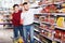 attentive couple choosing purchasing canned food for week at supermarket