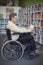 Attentive disabled school teacher reading book in library