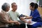 Attentive doctor or healthcare worker giving professional advice to senior couple during home visit