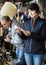 attentive elderly woman choosing interesting souvenirs at flea market