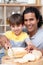 Attentive father helping his son cut some bread in