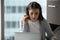 Attentive female student sitting in headphones by laptop studying online