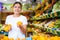 Attentive girl buyer chooses fresh oranges