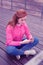 Attentive good-looking young girl sitting on the wooden coast and checking smartphone