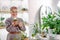 Attentive happy woman in blazer holding plant in pot