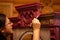 Attentive lady coloring massive wooden cupboard with astounding carved ornaments in red with brush with house walls in