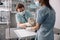 Attentive lady listens to cat on intravenous infusion while nurse assists in clinic