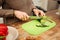 Attentive lady in warm sweater cutting cucumber while cooking