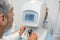 Attentive optometrist examining male patient on machine