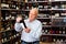 Attentive pensioner chooses red wine in a liquor store