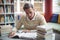 Attentive school teacher reading book in library