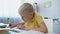 Attentive schoolboy doing homework, writing task in notebook, distant education