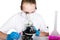 Attentive schoolgirl conducting a chemistry experiment at elementary science class. studying the bacteria through a