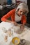 Attentive senior woman shaping a molded clay