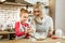 Attentive short-haired mother in apron showing her daughter process of cracking