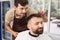 Attentive young barber combing client hair and enjoying his job