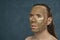 Attentively looking man with wet long hair in green clay mask on his face waiting of spa procedures