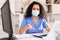 Attentively young female doctor in protective mask working at laptop in office