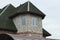 Attic of a gray private brick house with windows under a green tiled roof