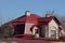 Attic gray private house with windows and red against the background of trees and sky