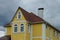 Attic of a large yellow private house with white windows under a brown tiled roof