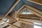 Attic space of a building under construction with wooden beams of a roof structure and brick walls. Real estate development