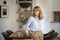 An attracive and blond haired woman cheerful smiling while standing at dining table at home