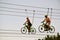 At the attraction, a guy and a girl ride on bicycles on hanging ropes and smile. Against the background of the blue sky