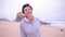 Attractive active mature woman running along ocean beach and smiling at camera.