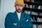 Attractive adult bearded angry man hipster in yellow hat looks at camera and furrowed his brows on books wall background