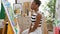 Attractive african american woman artist, sitting and concentrating, looking at beautiful draw in art studio