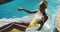 Attractive african american woman sitting on inflatable holding drink and smiling in swimming pool