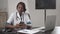 Attractive african medical doctor talking on telephone work with laptop, in cabinet hospital, write diagnosis