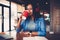 Attractive afro american student resting in coffee shop texting messages