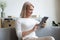 Attractive aged woman sitting on couch using tablet computer