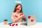 Attractive angelic woman with kind expression sitting covered with sticker love hearts, showing romantic heart shape