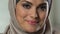 Attractive arab woman in headscarf smiling on camera, perfect make-up, wellness