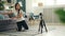 Attractive Asian blogger is installing camera on tripod and adjusting equipment then sitting on floor and recording