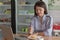 Attractive asian female enjoying slice of strawberry cake at cake store with laptop, smartphone and cup of coffee