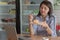 Attractive asian female enjoying slice of strawberry cake at cake store with laptop smartphone and cup of coffee