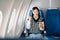 Attractive Asian female passenger of airplane sitting in comfortable seat while working laptop and tablet with mock up area using