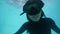 Attractive asian girl in snorkeling mask diving in pool and swimming underwater.