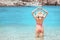 Attractive Asian woman in a closed striped swimsuit is resting on the resort beach on the coast of the calm azure sea