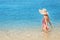 attractive Asian woman in a closed striped swimsuit is resting on the resort beach on the coast of the calm azure sea