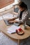 Attractive Asian woman focuses on working on her tasks, using a laptop in a living room